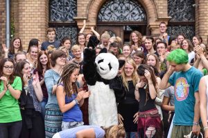 Ein Panda in der Mitte um den viele Jugendliche herumstehen