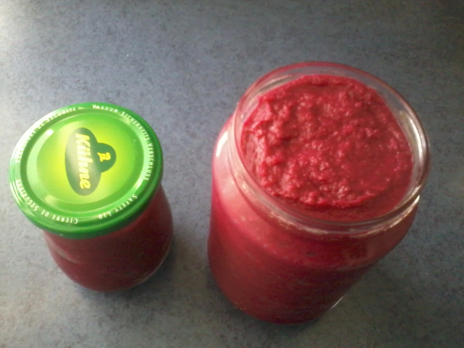 Das Foto zeigt zwei Gläser mit Rote-Bete-Hummus. Eines ist offen, ein Glas ist geschlossen.