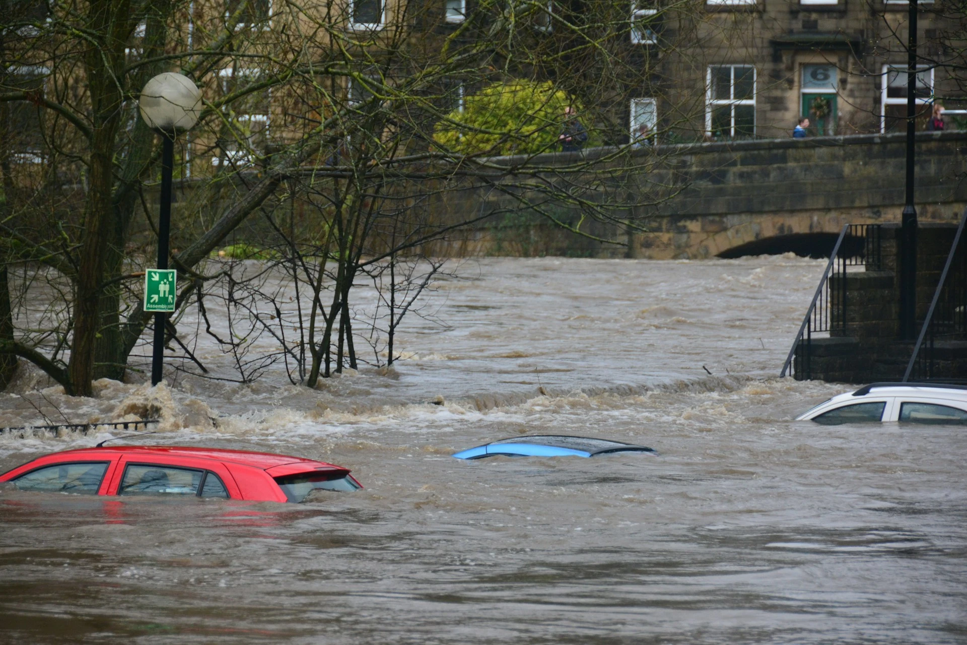 Das Foto zeigt eine überschwemmte Straße. Aus dem Wasser schauen die Dächer der Autos hervor,