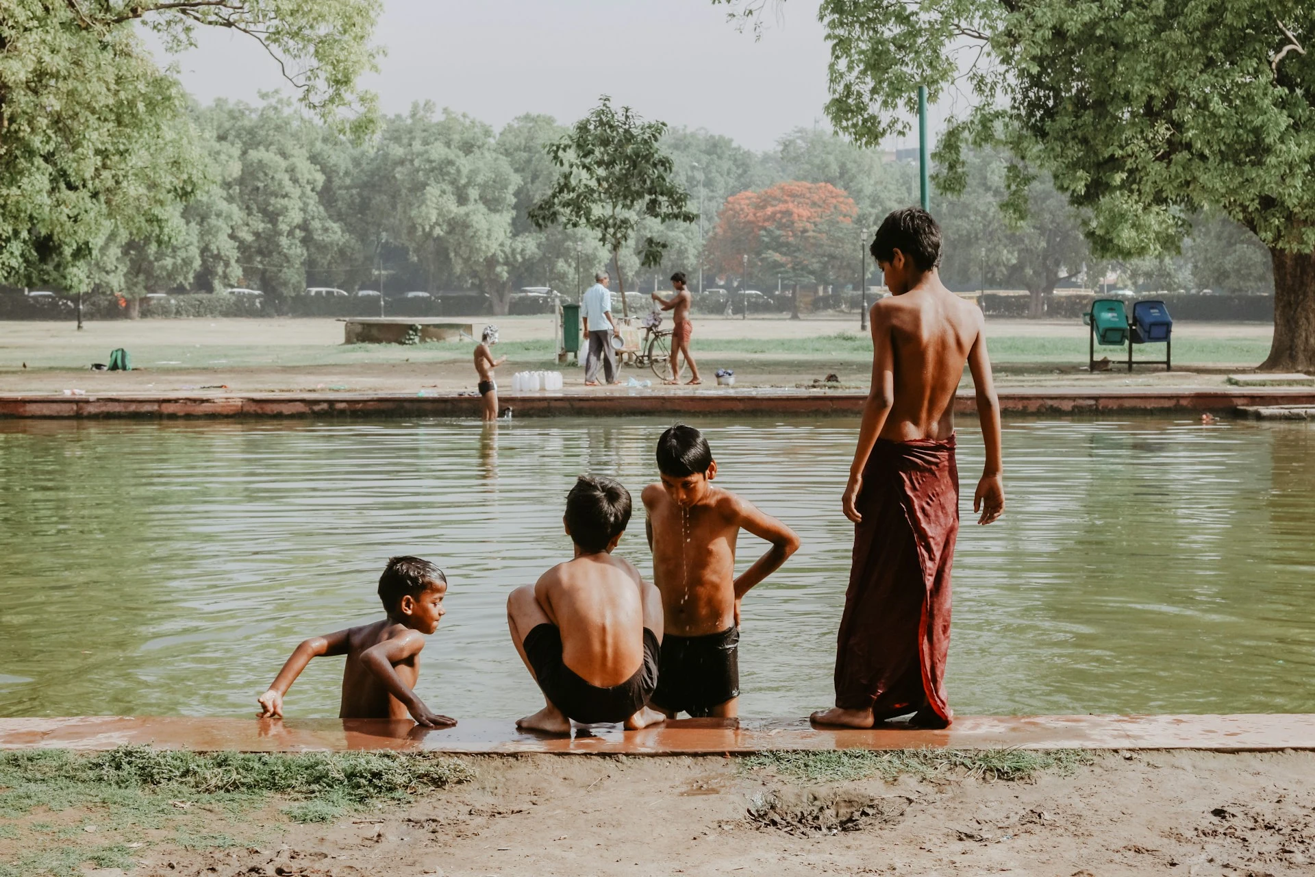 Das Foto zeigt 4 indische Kinder an einem Becken mit Wasser.