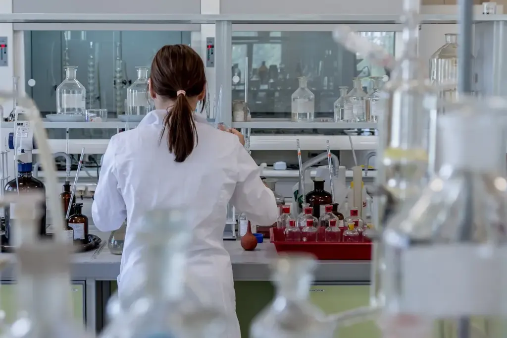 Eine Person steht vor einem Tisch voller Pipetten, Gläser und anderen Laborgeräten