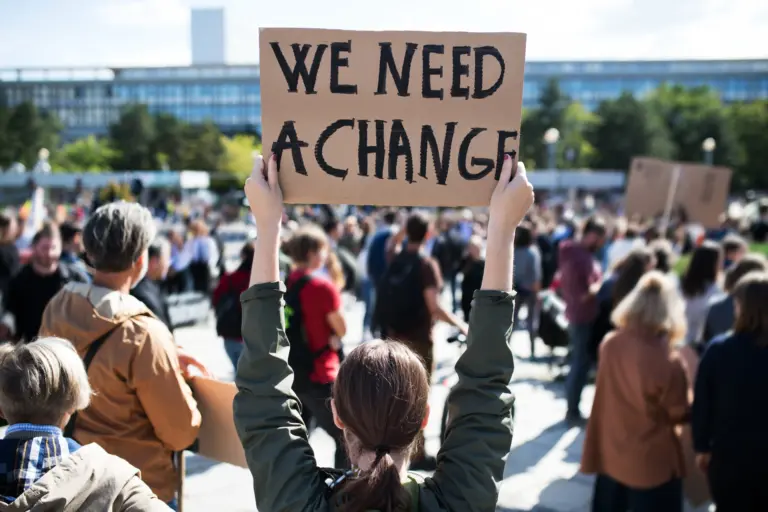 Eine Protestierende mit Schildern, die für Veränderung demonstrieren.