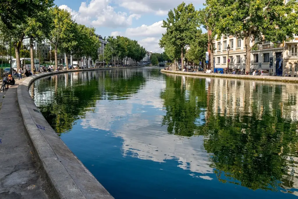 ein Fluss fließt durch eine Stadt, an der Ufermauer stehen Bäume