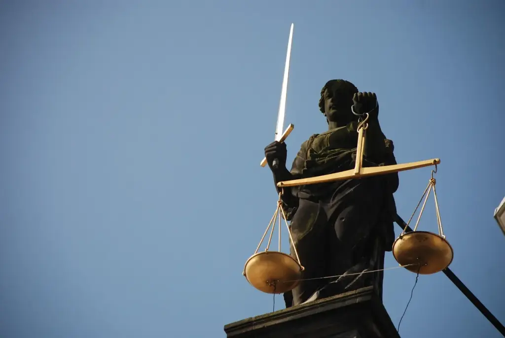 Justiitia mit Waage und Schwert vor blauem Himmel