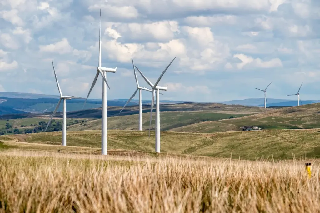 mehrere Windkraftanlagen stehen in einer leicht hügeligen Landschaft
