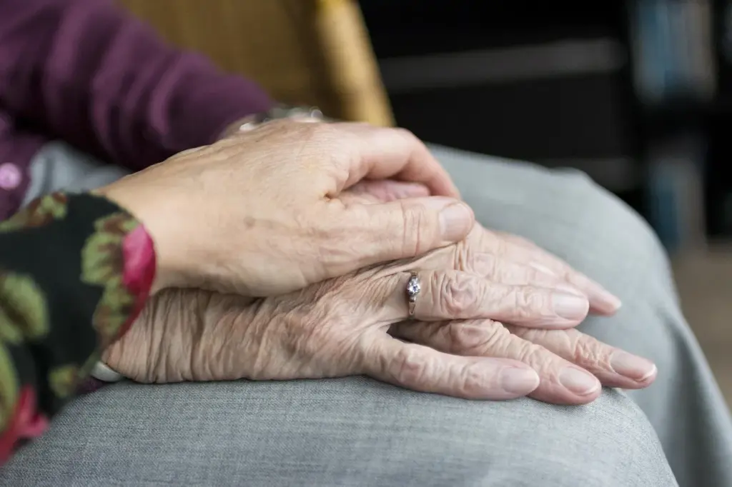 Eine Hand hält die Hände einer älteren Frau