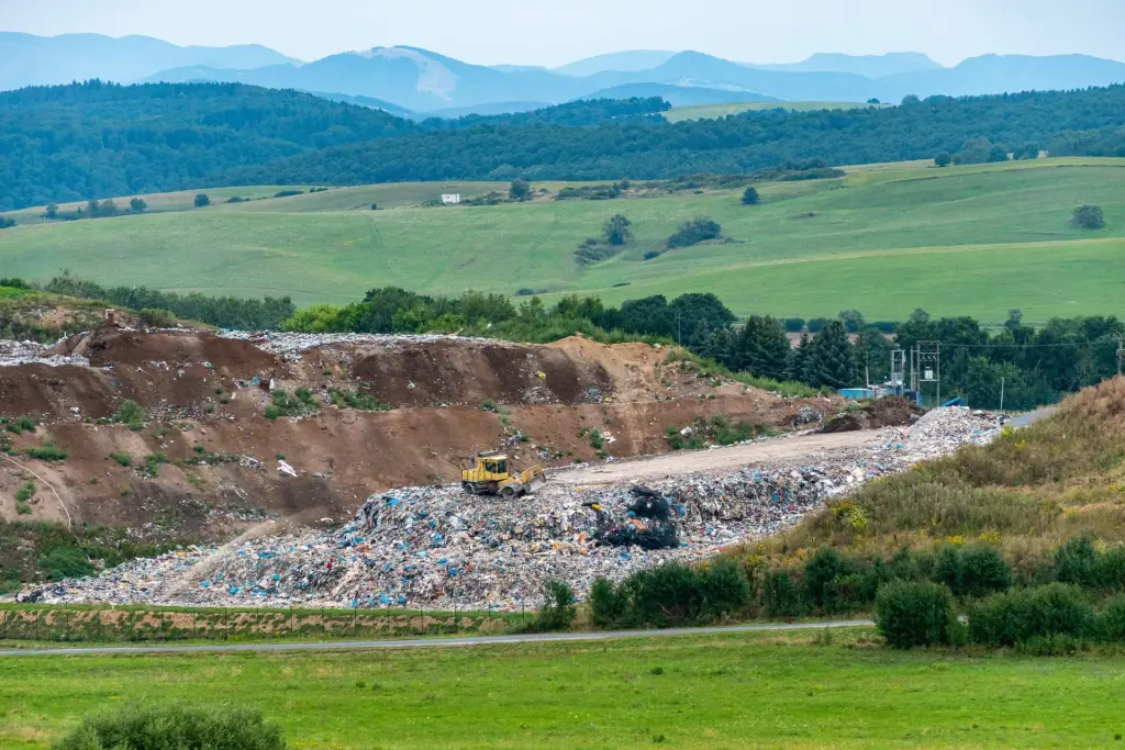 Das Bild zeigt eine Deponie mit einem Bagger in der Landschaft.